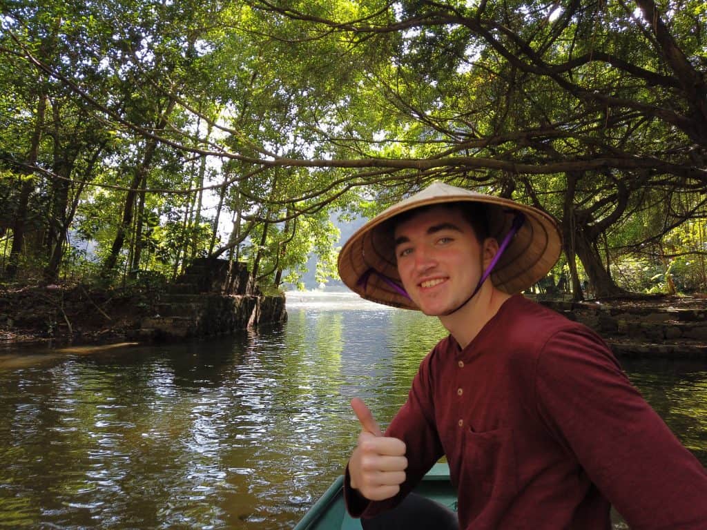 Happy european with conicle hat on the Tam Coc boat tour in Ninh Binh